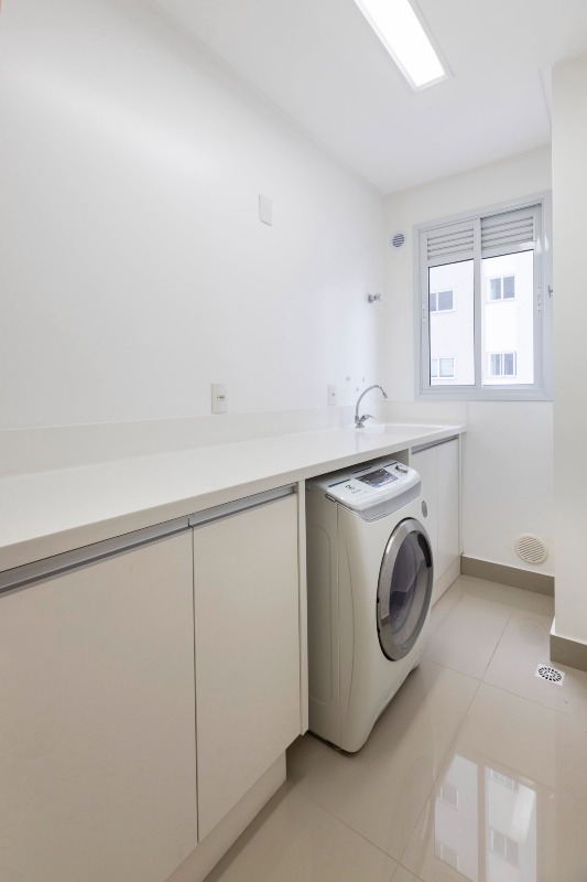 Apartamento à venda no Centro: Área de serviço com bancada branca, cuba e máquina de lavar