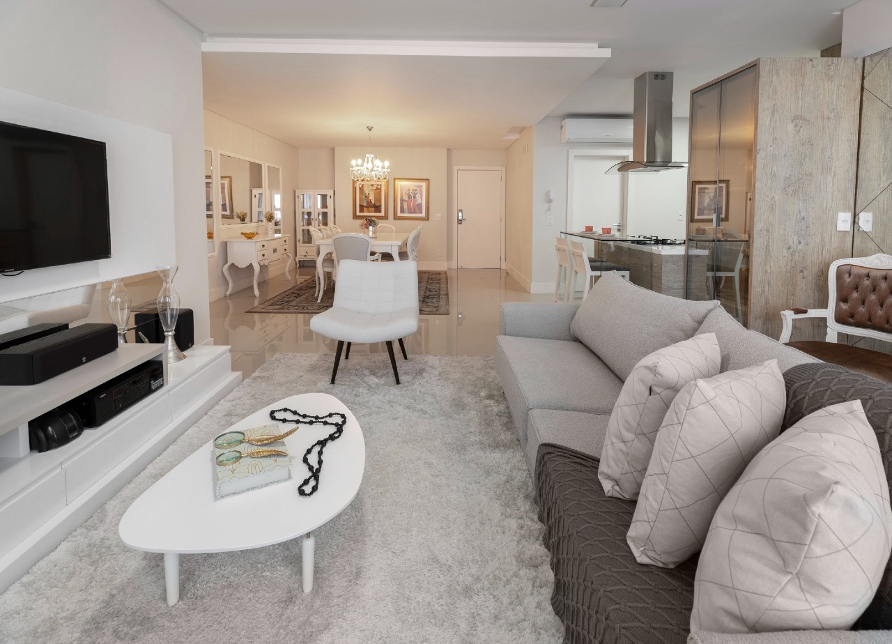 Apartamento à venda no Centro: Estar com painel de TV e sofá, com a sala de jantar e a cozinha ao fundo