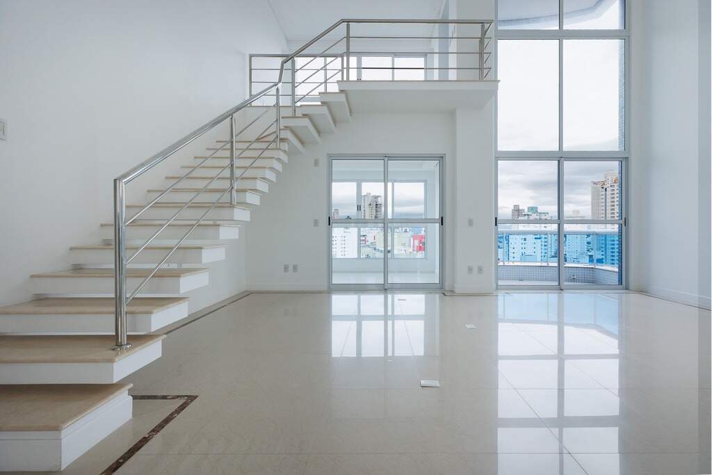 Apartamento à venda no Centro: Living com pé-direito duplo, escada para o mezanino e porta de vidro para a sacada
