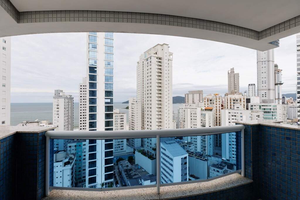 Apartamento à venda no Centro: Sacada com vista parcial para o mar entre os prédios do Centro de Balneário Camboriú