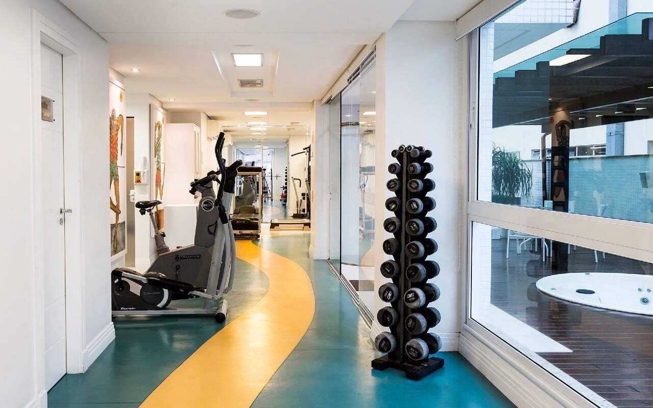 Apartamento à venda no Centro: Academia com bicicleta, elíptico e halteres, de frente para o deck da hidromassagem