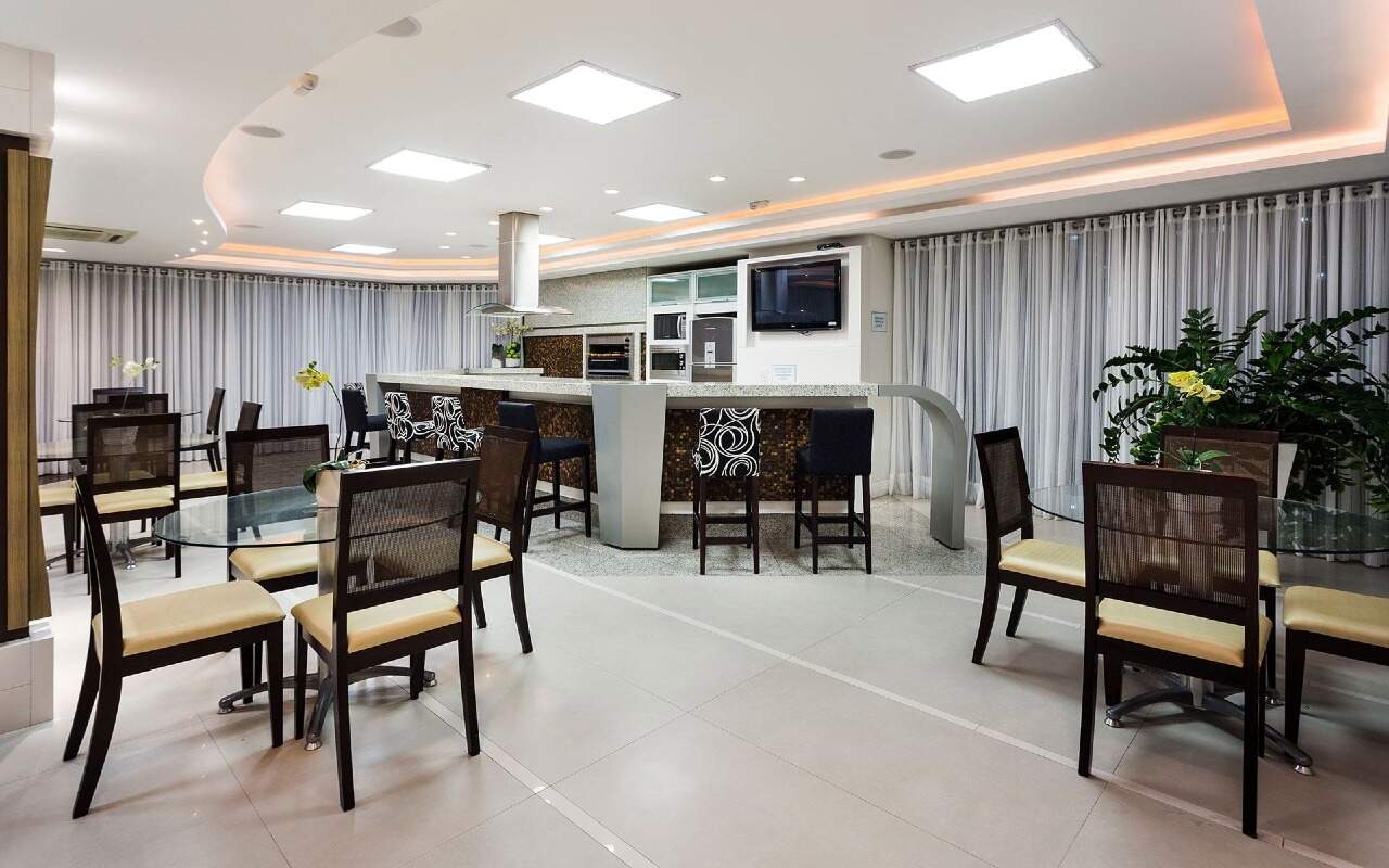 Apartamento à venda no Centro: Salão de festas com cozinha equipada, bancada e mesas de vidro