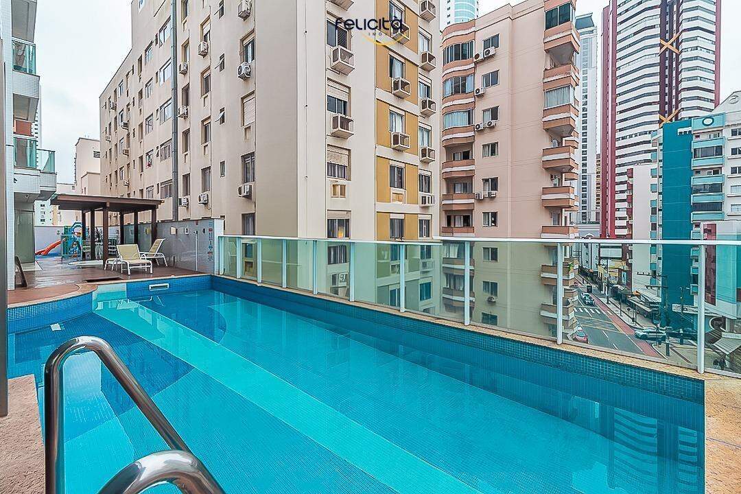 Apartamento à venda no Centro: Piscina do prédio, com guarda-corpo de vidro e espreguiçadeiras junto ao deck