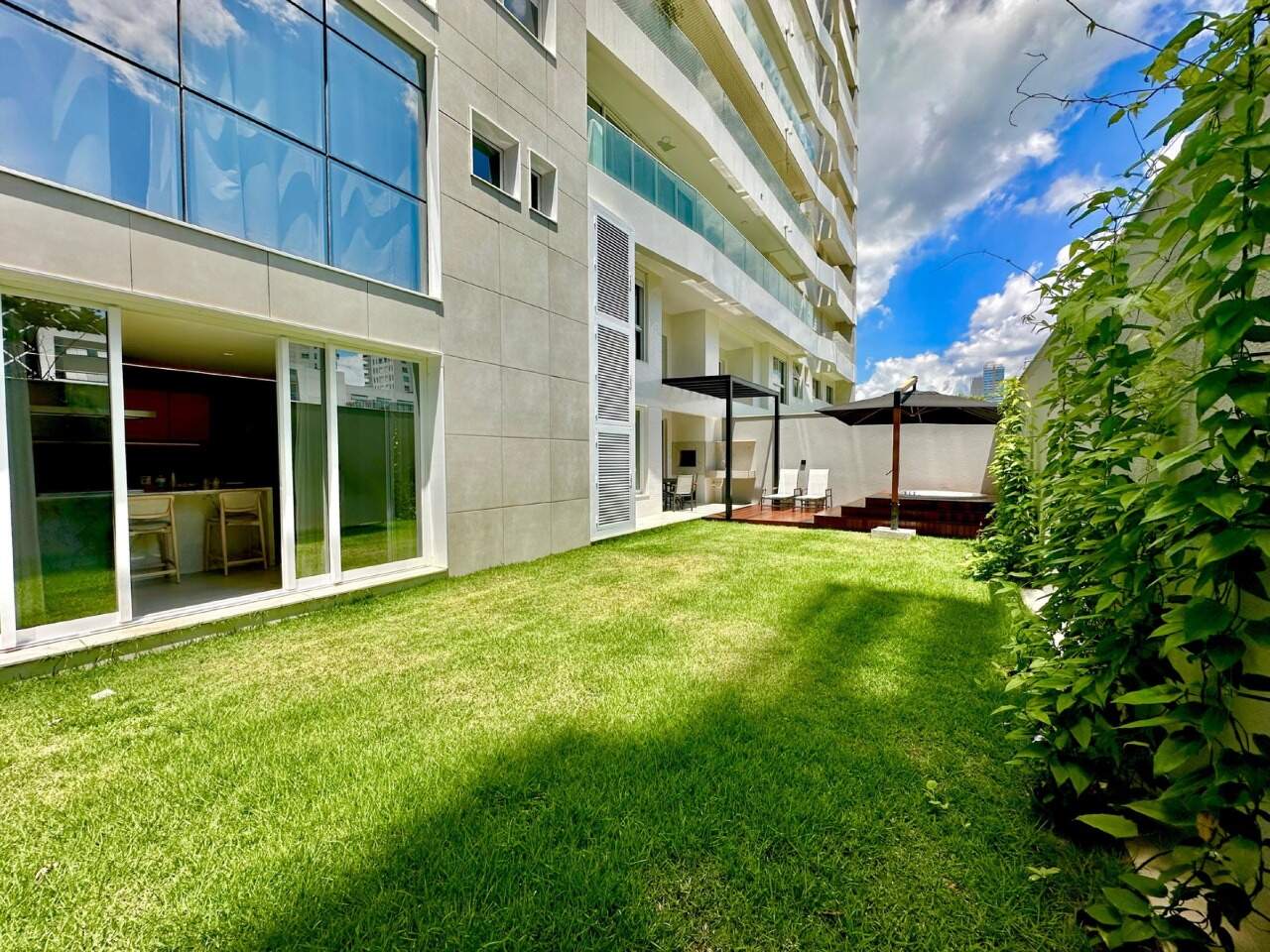Apartamento diferenciado à venda no Praia Brava: Jardim gramado privativo ao longo da fachada de vidro, com o deck ao fundo