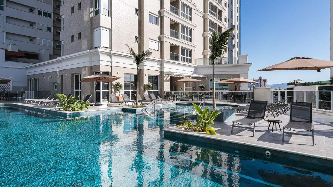 Apartamento à venda no Centro: Piscina do Hamptons Village com palmeiras, deck e guarda-sóis