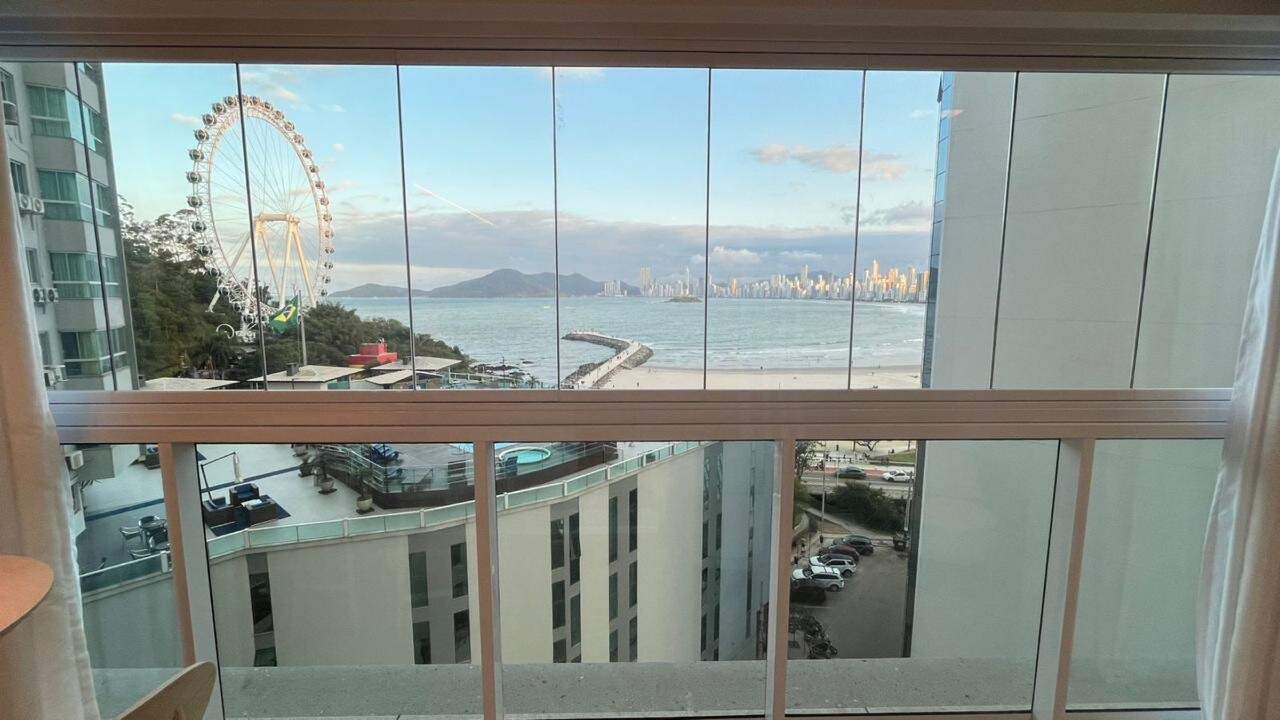 Apartamento à venda no Pioneiros: Vista da sacada: o mar, a roda-gigante e a orla de Balneário Camboriú, entre prédios vizinhos