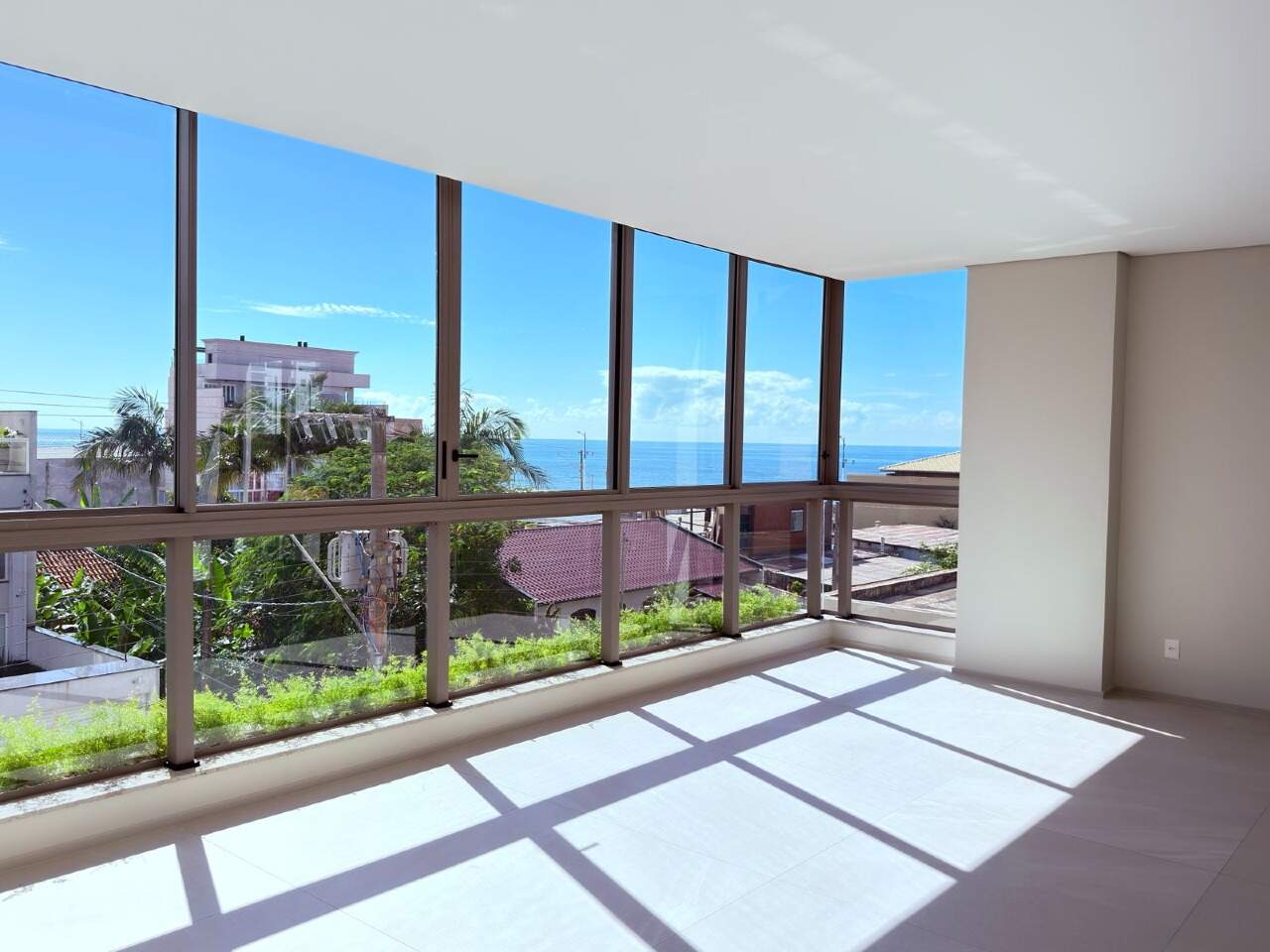Apartamento à venda no Praia Brava: Ambiente integrado com vidro do piso ao teto e o mar à direita