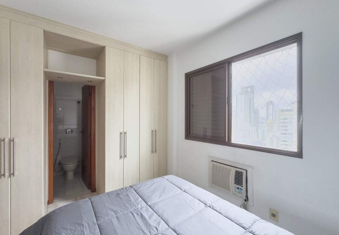 Apartamento à venda no Centro: Suíte com armários, porta do banheiro e ar-condicionado sob a janela