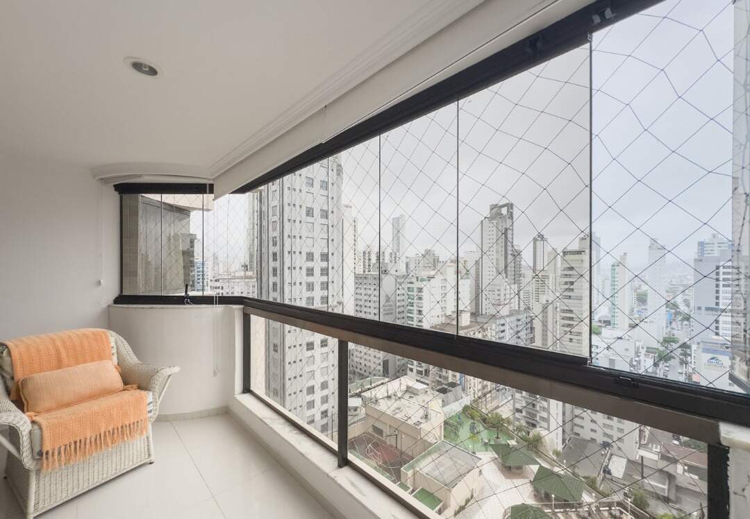 Apartamento à venda no Centro: Ponta da sacada com poltrona e vista da cidade sobre a área de lazer do prédio