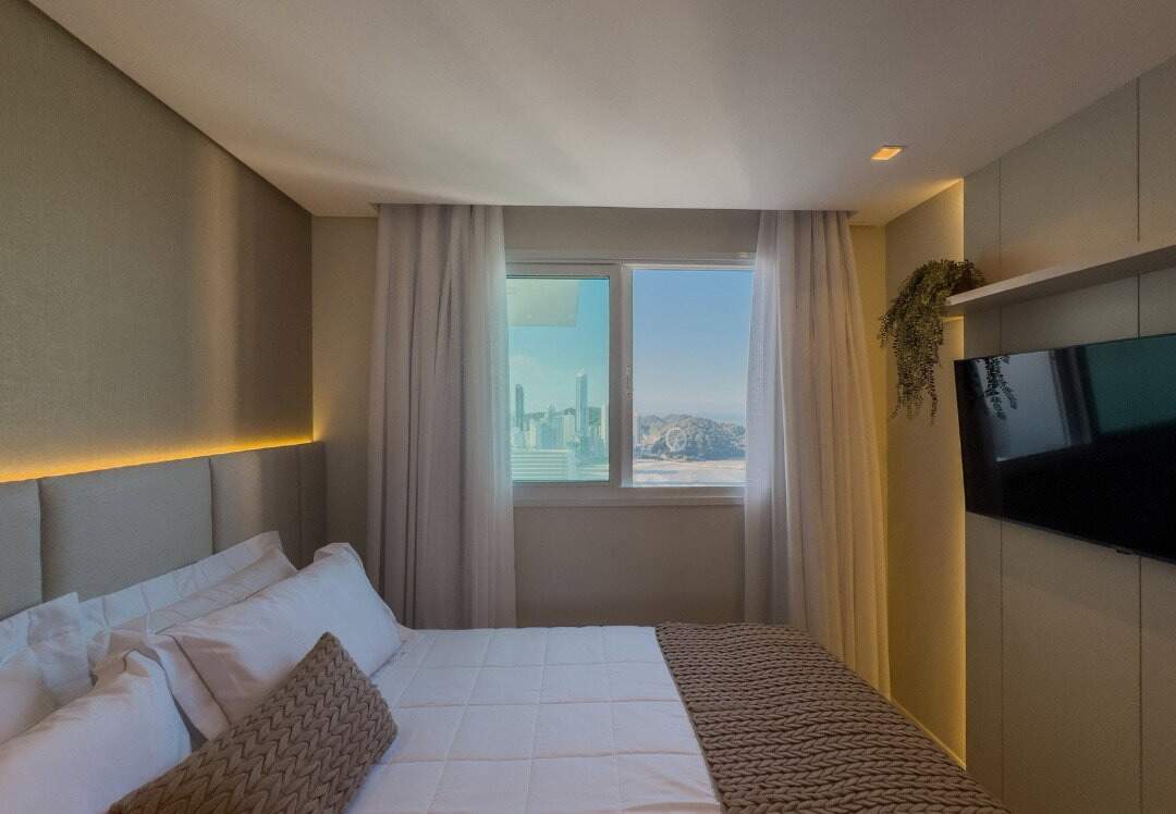 Apartamento à venda no Centro: Dormitório com janela para o mar e painel de TV