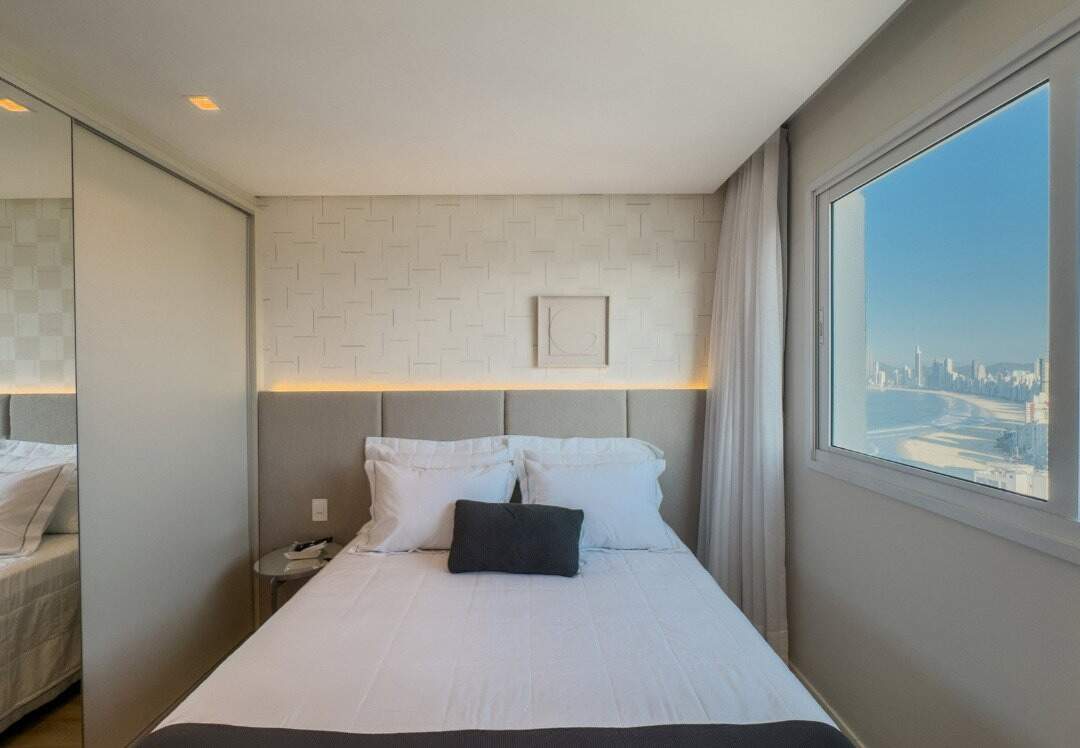 Apartamento à venda no Centro: Dormitório com cabeceira estofada e vista para a praia