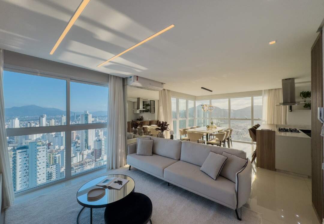 Apartamento à venda no Centro: Living integrado com sofá, painel de TV e janelas para a cidade e os morros