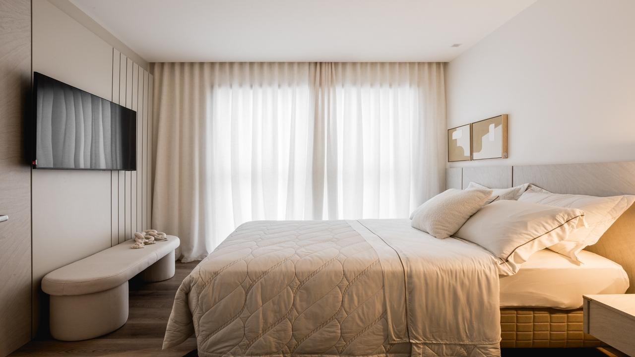 Apartamento diferenciado à venda no Centro: Suíte com cortinas claras e banco aos pés da cama (imagem ilustrativa)