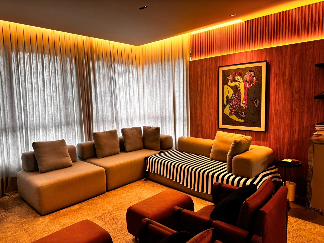 Apartamento à venda no Centro: Living com sofá em L, poltronas e painel ripado de madeira com quadro