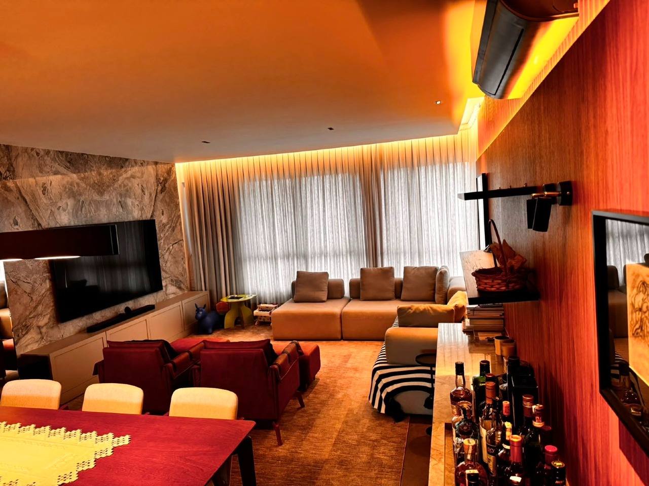 Apartamento à venda no Centro: Living com painel de pedra para a TV, sanca iluminada e cortinas do piso ao teto
