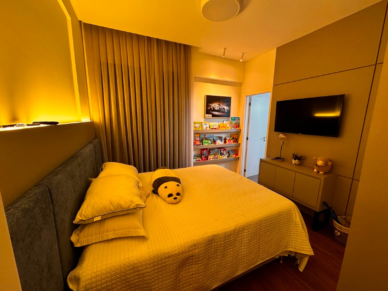 Apartamento à venda no Centro: Suíte com painel de madeira iluminado, TV e nichos para livros