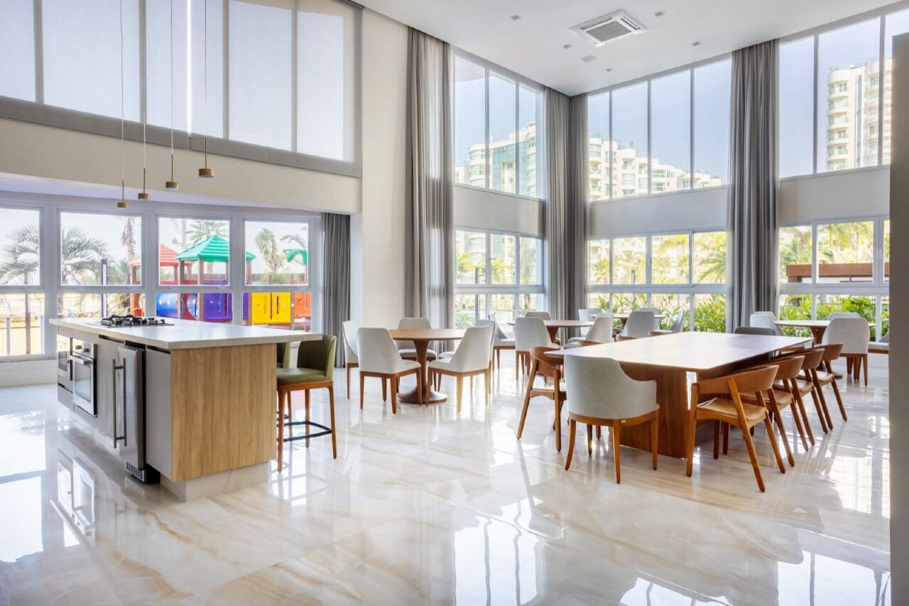 Apartamento à venda no Praia Brava: Salão com cozinha, ilha e mesas, com janelas altas para o lazer