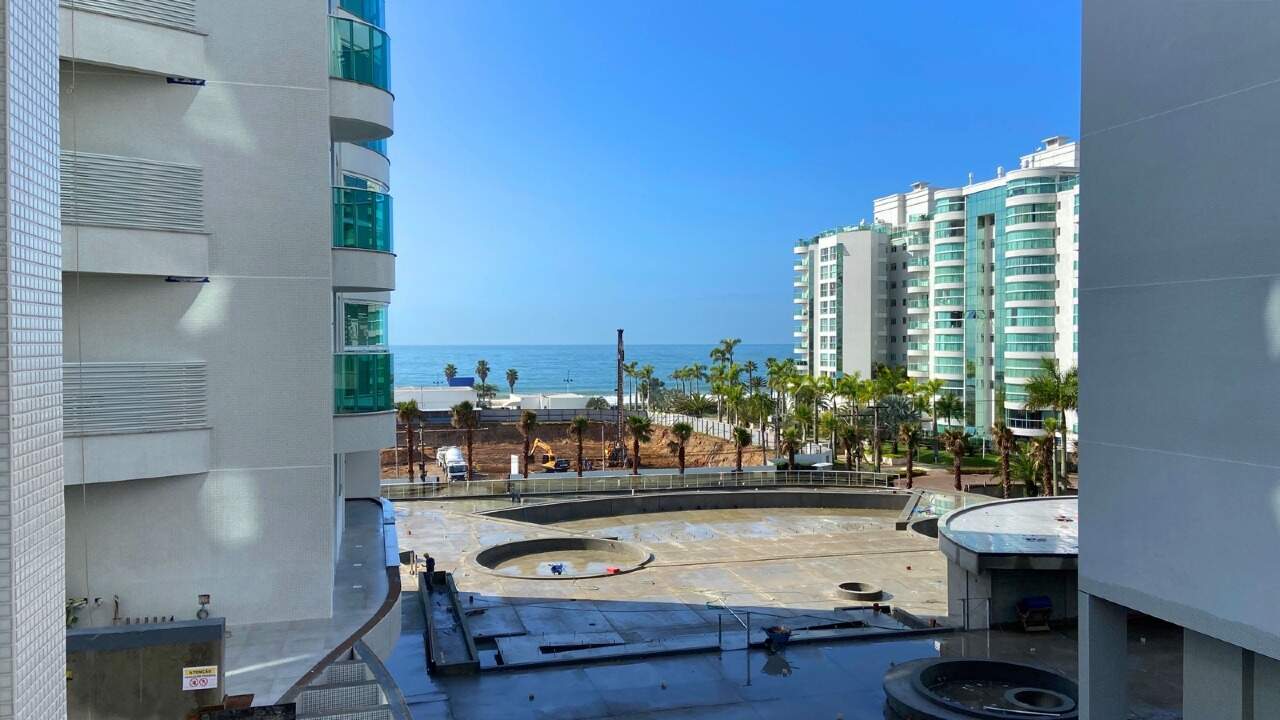 Apartamento à venda no Praia Brava: Sacada curva com guarda-corpo de vidro e o mar visto entre prédios