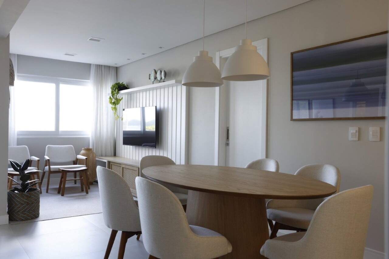 Apartamento à venda no Centro: Sala de jantar com mesa oval e painel ripado com TV