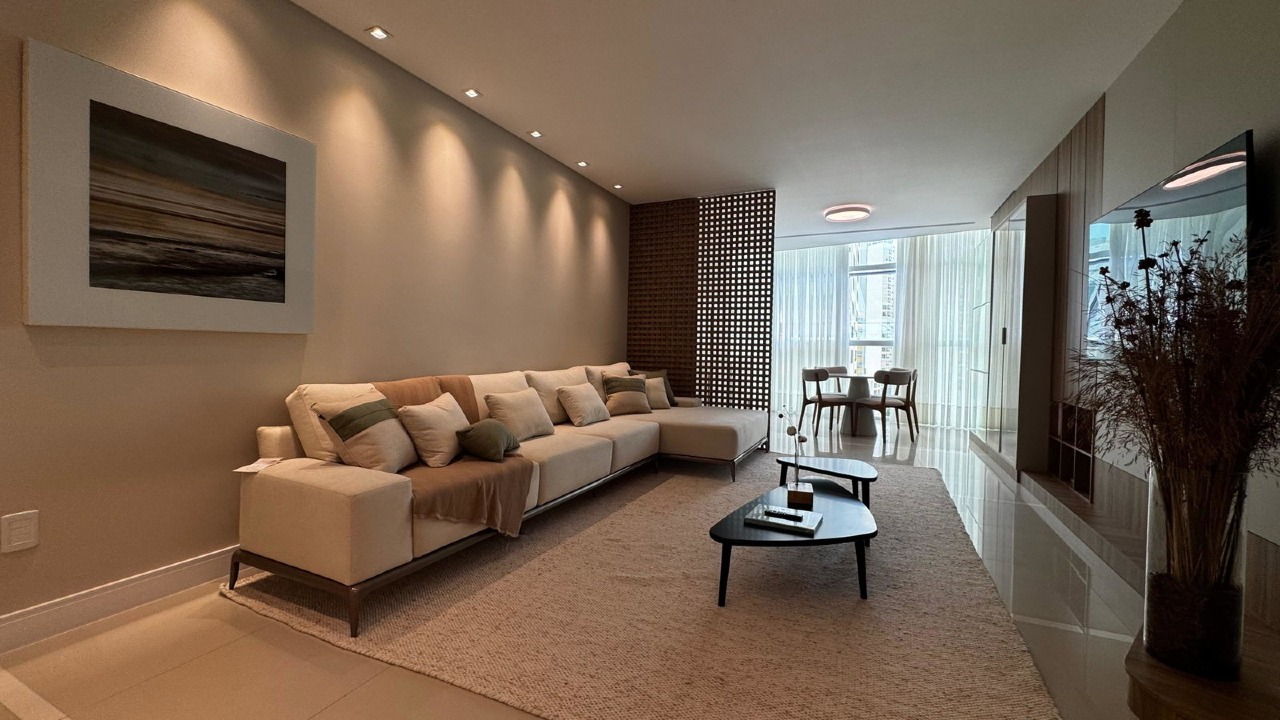 Apartamento à venda no Centro: Living decorado com sofá em L, painel de TV e iluminação embutida no forro de gesso