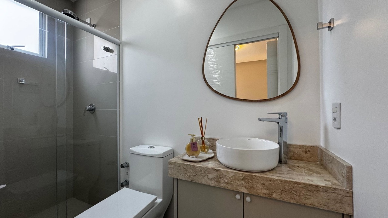 Apartamento à venda no Centro: Banheiro com bancada de pedra, cuba de apoio e box de vidro