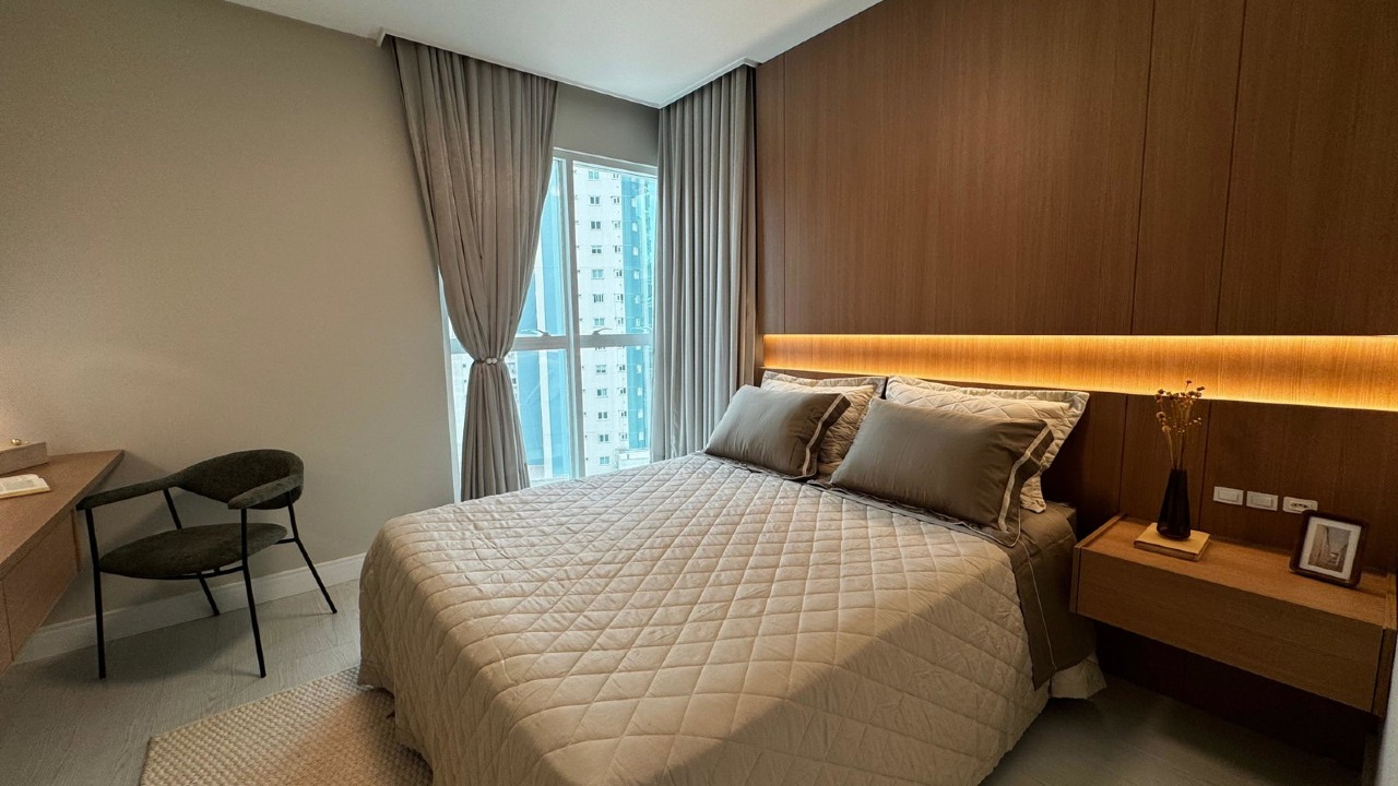 Apartamento à venda no Centro: Suíte principal com cabeceira em painel de madeira e iluminação indireta
