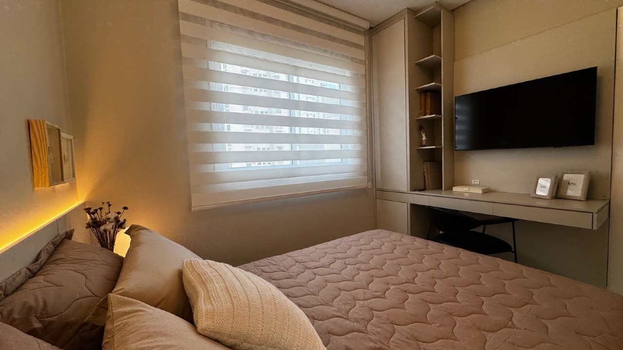 Apartamento à venda no Centro: Suíte com escrivaninha, TV e cortina de rolo