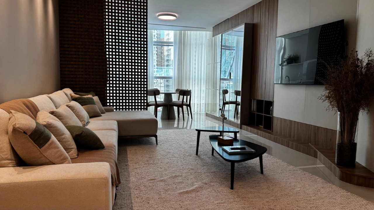 Apartamento à venda no Centro: Estar integrado ao pano de vidro, com painel de TV em madeira e cortinas