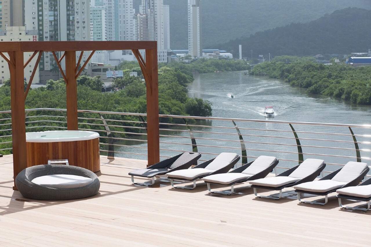 Apartamento à venda no Centro: Solário do deck com espreguiçadeiras e ofurô diante do Rio Camboriú