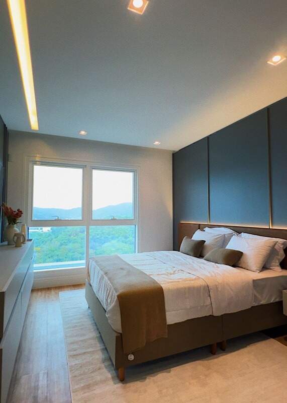 Apartamento à venda no Centro: Suíte com cabeceira em painel azul e janela para o verde