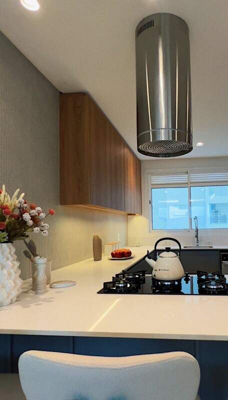 Apartamento à venda no Centro: Cooktop com coifa inox e bancada clara na cozinha