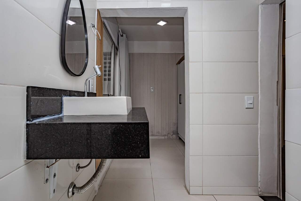 Apartamento à venda no Centro: Lavabo com bancada preta e espelho