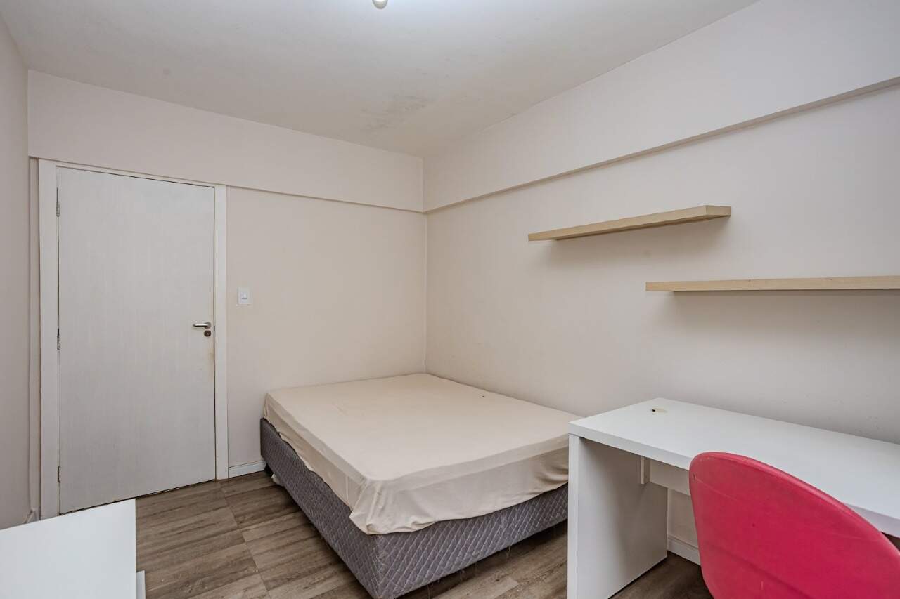 Apartamento à venda no Centro: Quarto com cama e prateleiras na parede