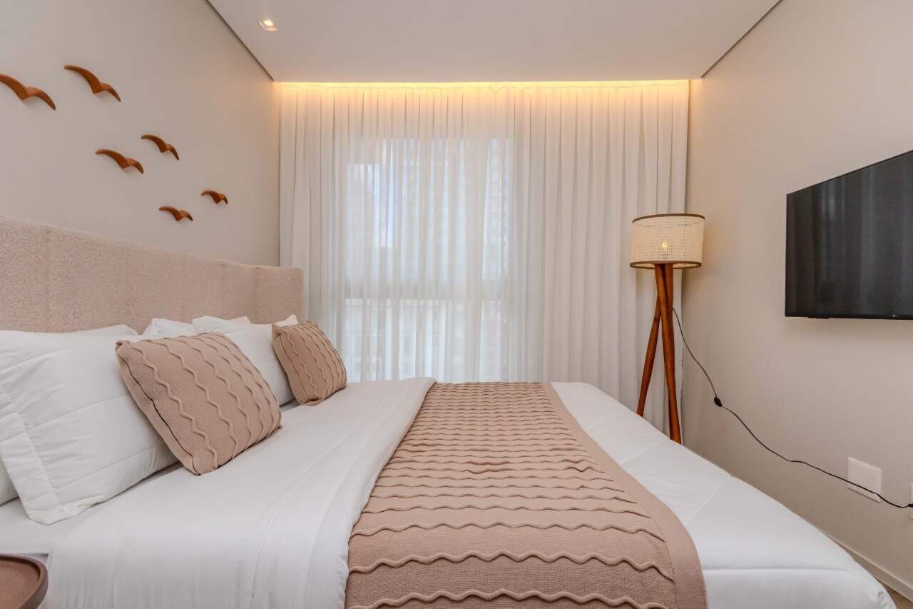 Apartamento à venda no Praia Brava: Suíte com TV, luminária de piso e iluminação indireta