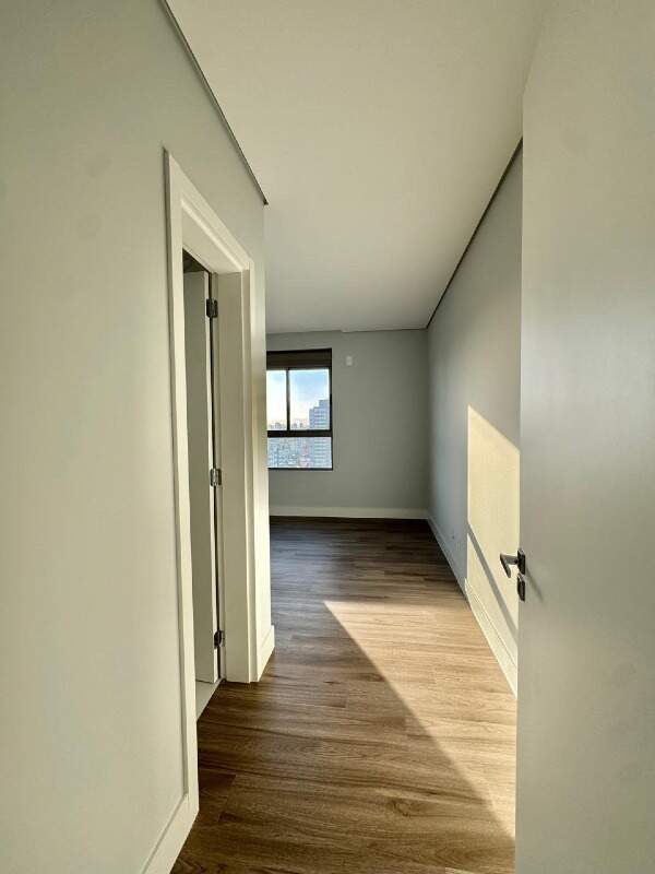 Apartamento à venda no Centro: Dormitório com piso amadeirado visto da entrada, com a janela ao fundo