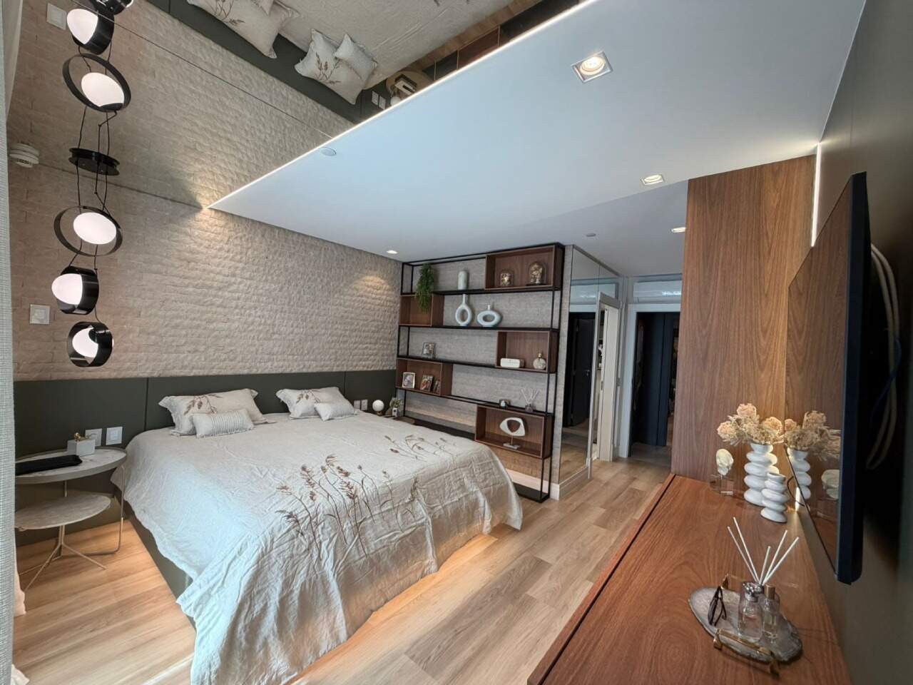 Apartamento à venda no Barra Sul: Suíte master com parede de tijolinho branco, estante e luminárias pendentes