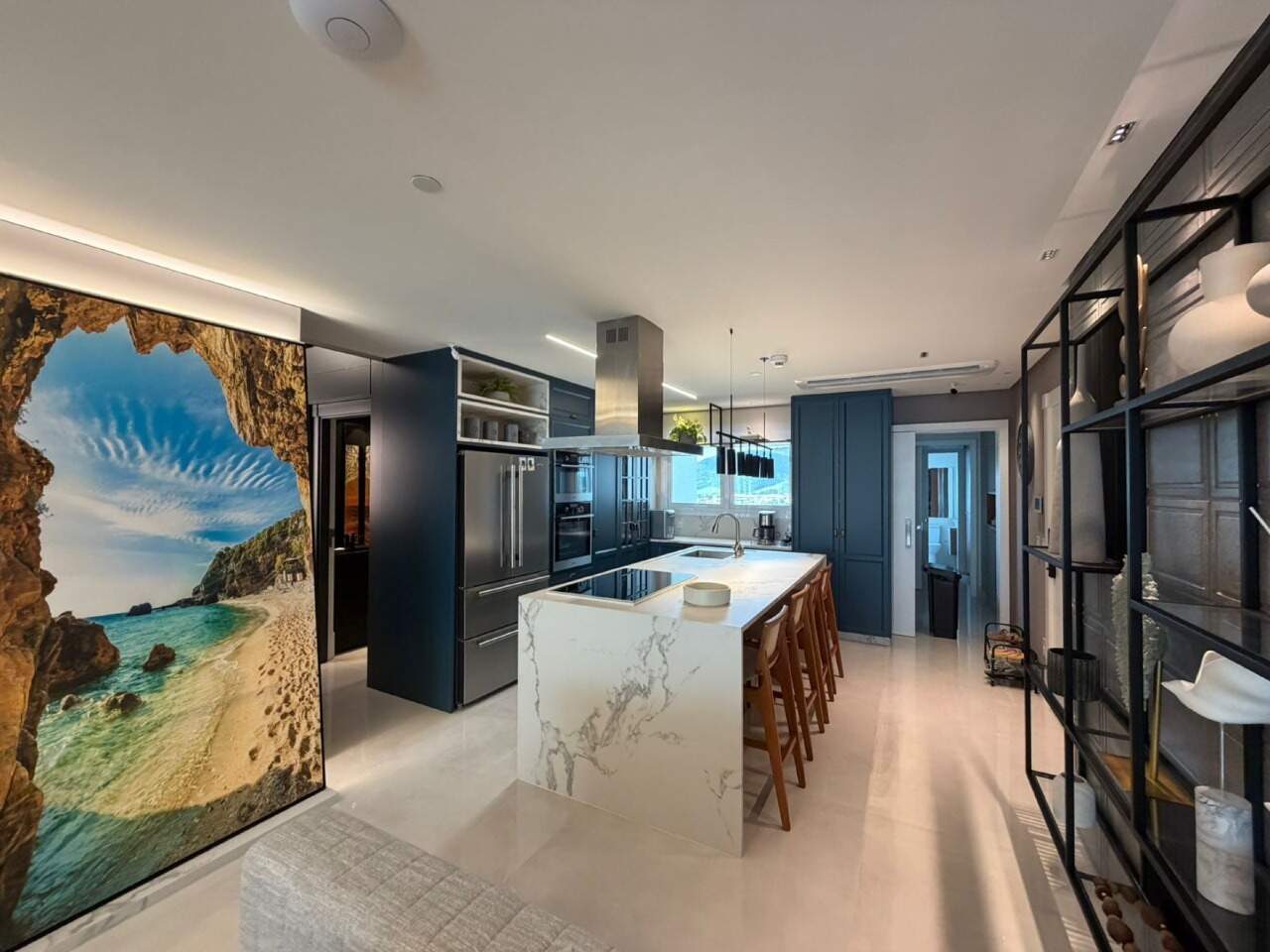 Apartamento à venda no Barra Sul: Cozinha integrada ao living, com painel de paisagem de praia e estante de metal