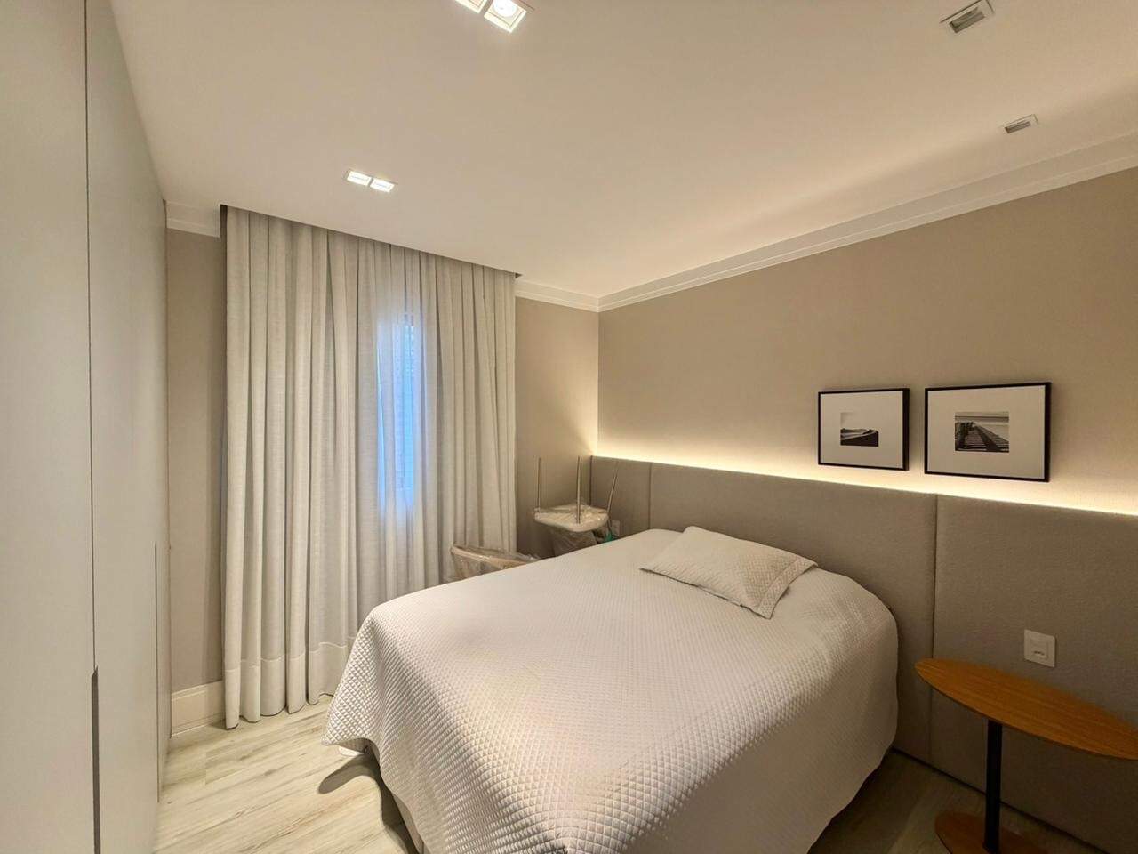 Apartamento à venda no Centro: Suíte com cabeceira estofada, mesa de cabeceira e cortinas
