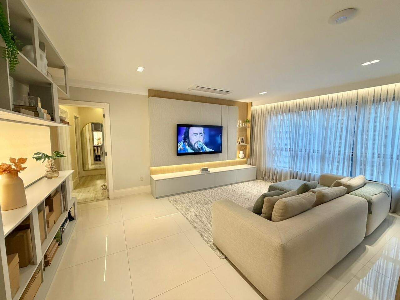 Apartamento à venda no Centro: Living com painel de TV, estante planejada e cortinas do piso ao teto