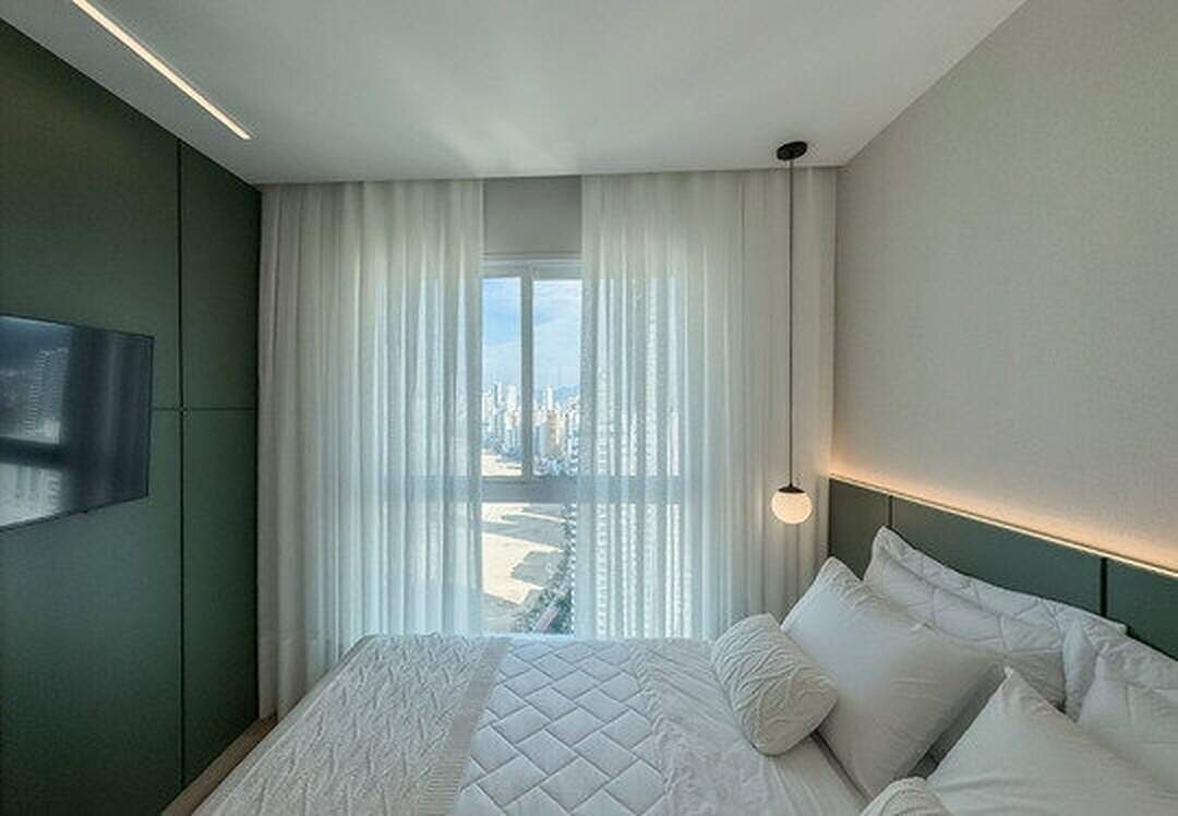 Apartamento à venda no Pioneiros: Suíte com painel verde, pendente e janela para a Praia Central