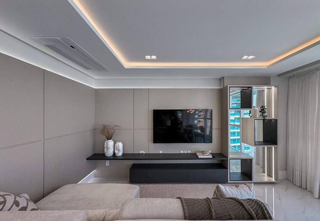 Apartamento à venda no Pioneiros: Estar com sofá, painel de TV e estante iluminada