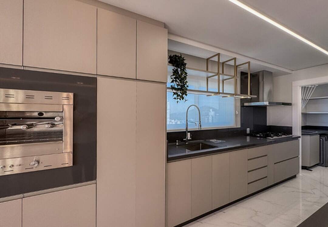 Apartamento à venda no Pioneiros: Cozinha com forno embutido, cooktop e janela sobre a pia