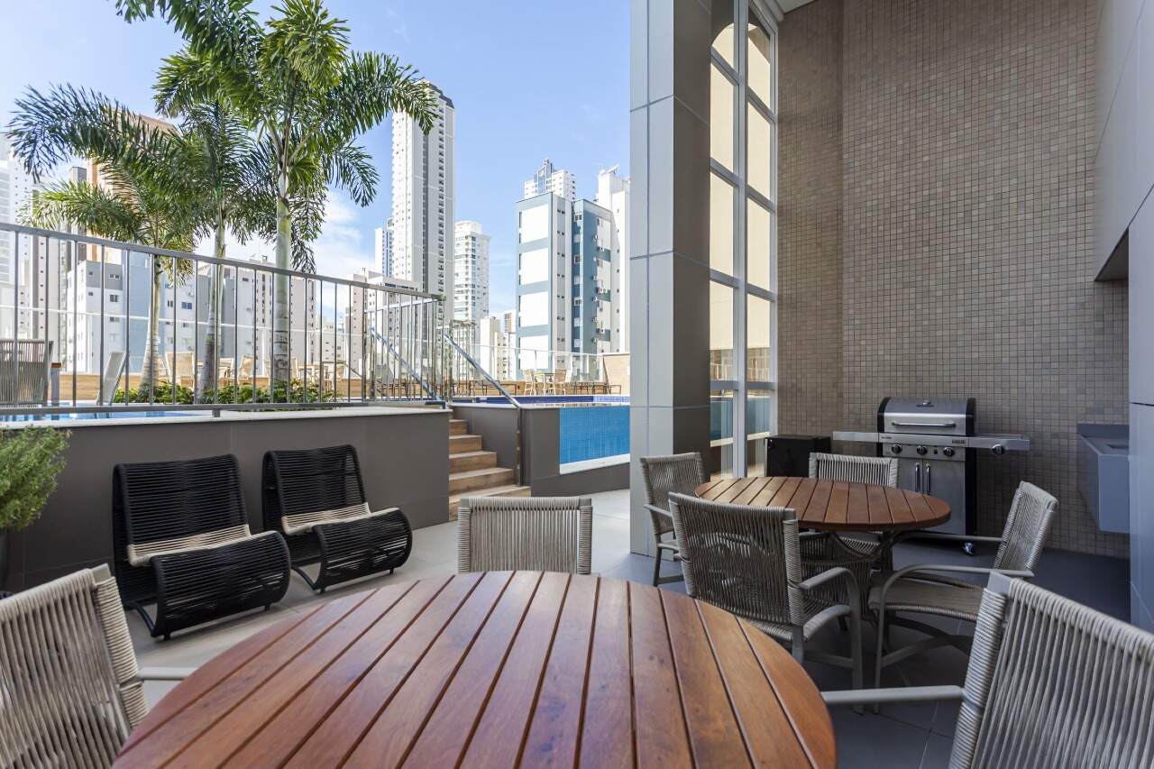Apartamento à venda no Centro: Quiosque com churrasqueira, mesa redonda e estar ao lado da piscina