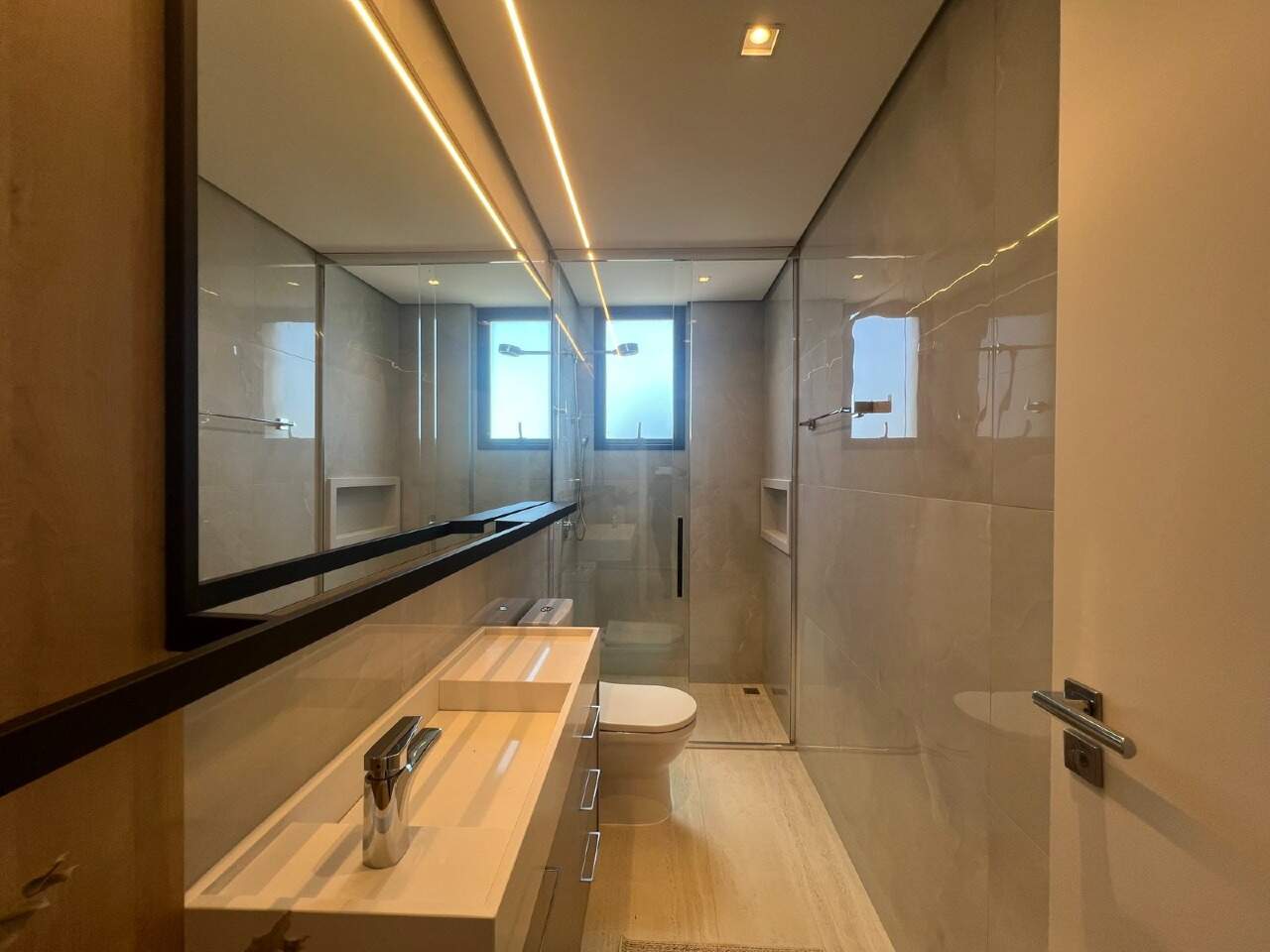 Apartamento à venda no Praia Brava: Banheiro com bancada iluminada e box de vidro (foto real)