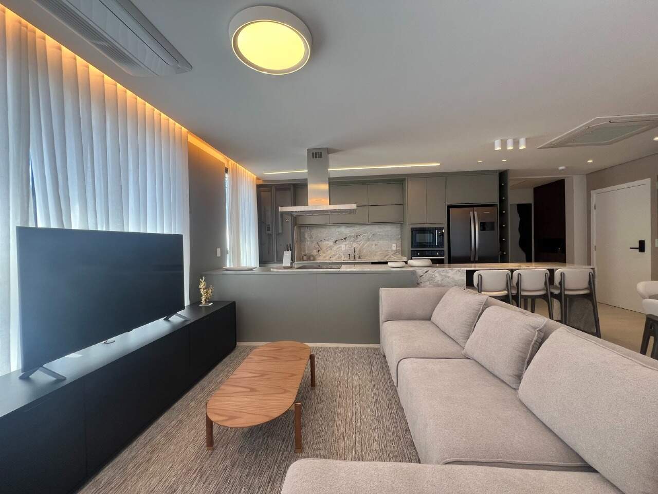 Apartamento à venda no Praia Brava: Living com sofá e cozinha ao fundo em apartamento decorado (foto real de outra unidade)