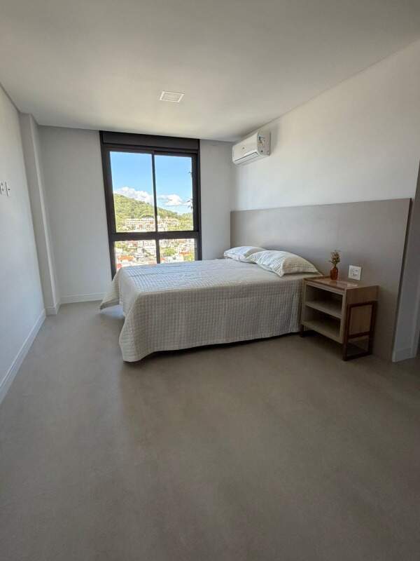 Apartamento à venda no Praia Brava: Suíte com mesa de cabeceira e vista para os morros