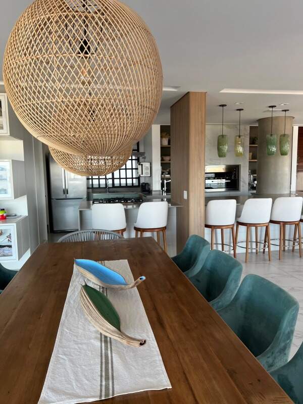 Apartamento à venda no Praia Brava: Mesa de jantar de madeira com cadeiras verdes e a cozinha ao fundo