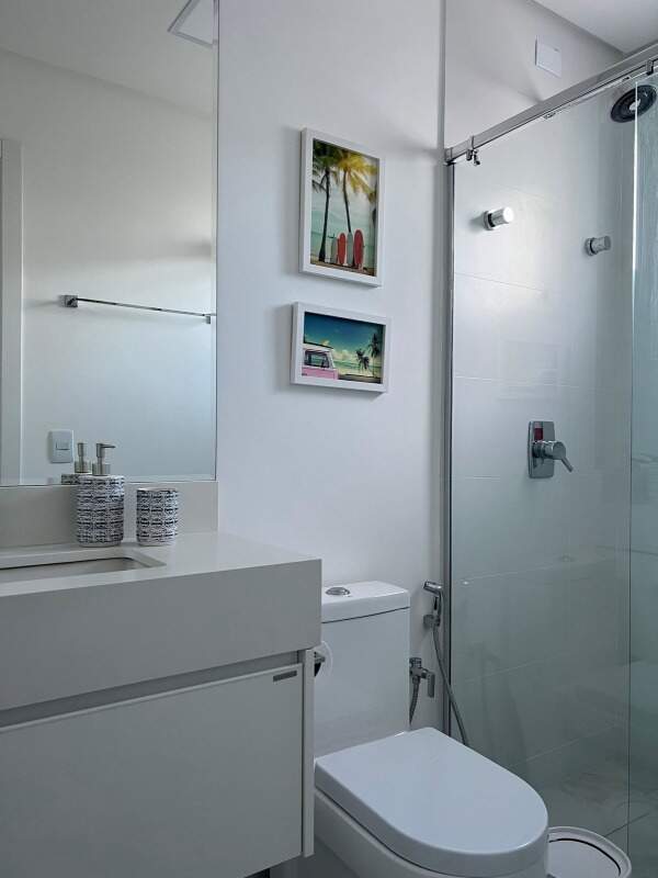 Apartamento à venda no Praia Brava: Banheiro com box de vidro e quadros de praia