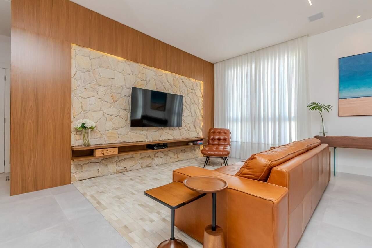 Apartamento à venda no Praia Brava: Estar com painel de pedra, TV e poltrona