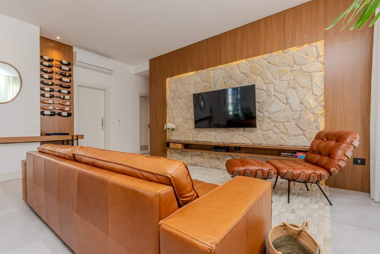 Apartamento à venda no Praia Brava: Living com sofá de couro e painel de pedra